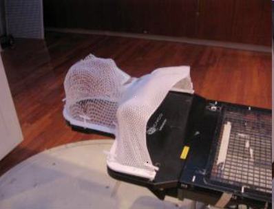 Photo of a white mesh radiation mask shaped like a person's head and shoulders.